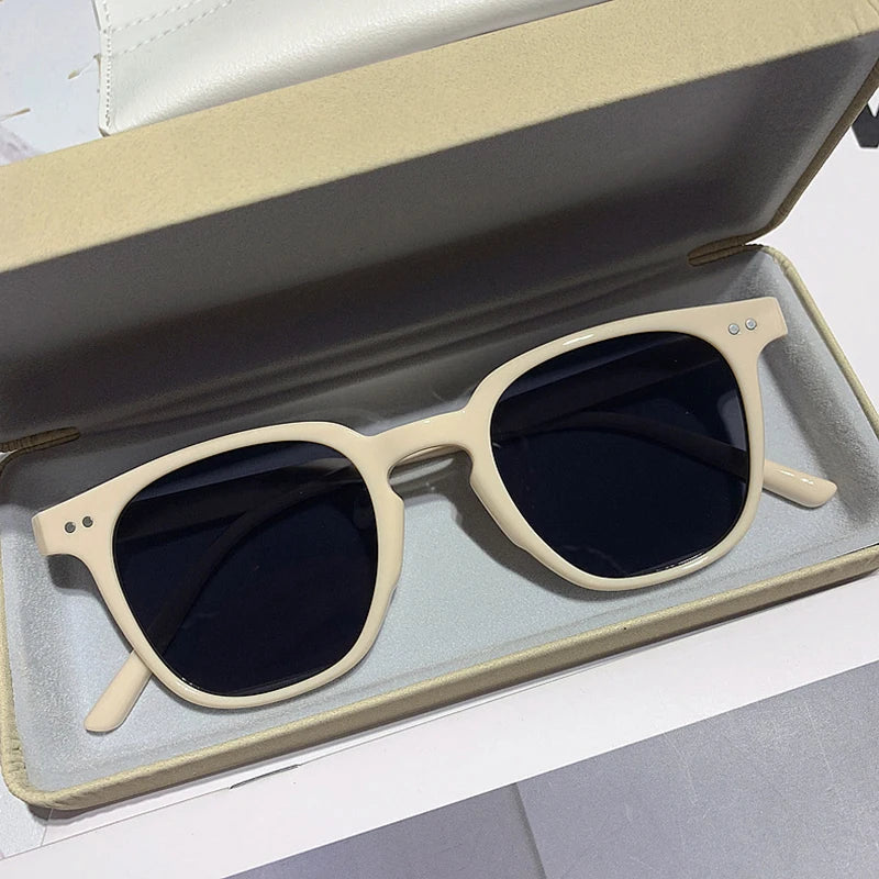 Lunettes de soleil élégantes à monture beige dans un étui ouvert, verres teintés noirs, accessoire de mode tendance pour protection solaire.