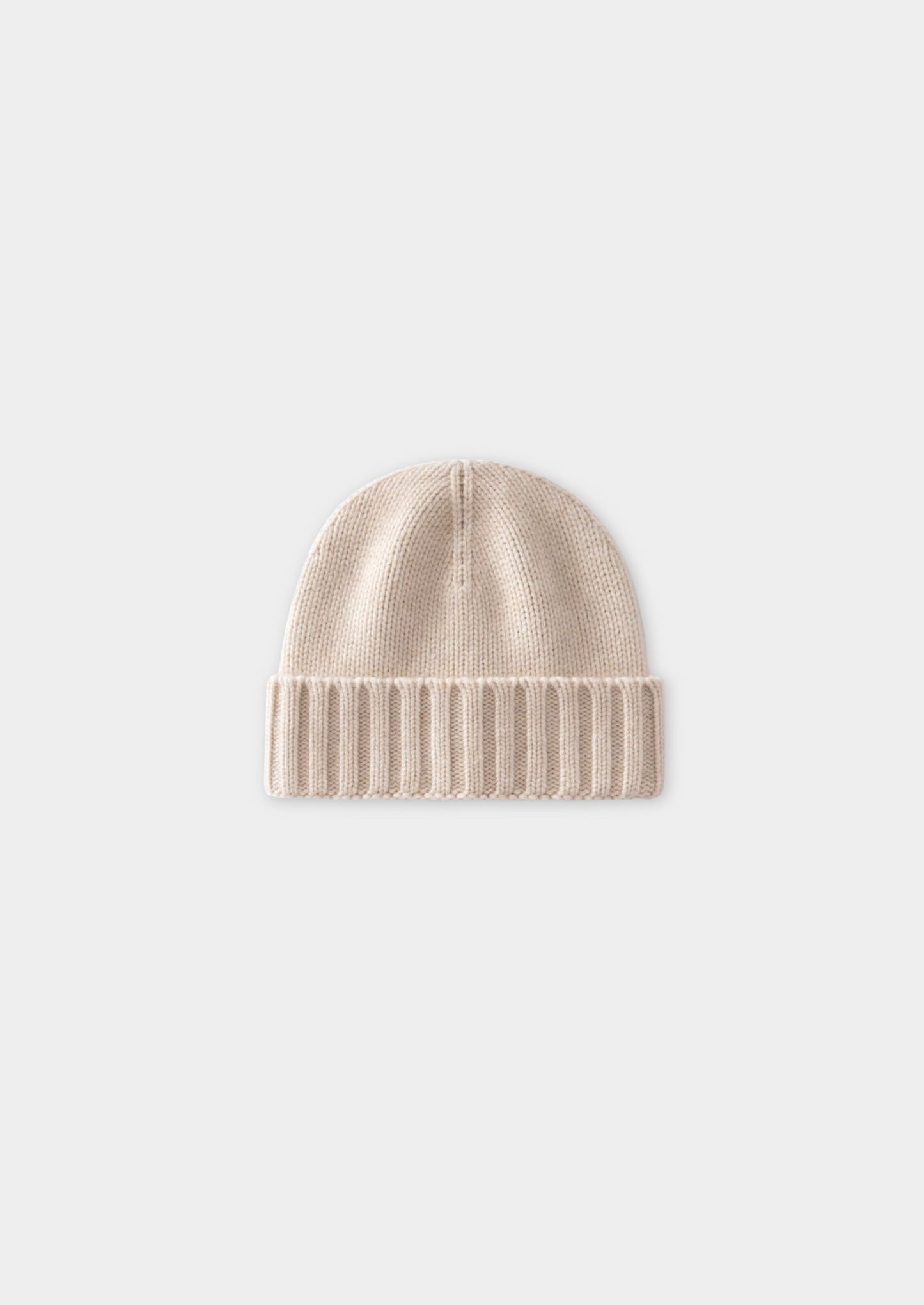 Bonnet en laine beige sur fond blanc, tricoté avec revers côtelé. Accessoire d'hiver élégant et chaud, idéal pour la mode automne-hiver.