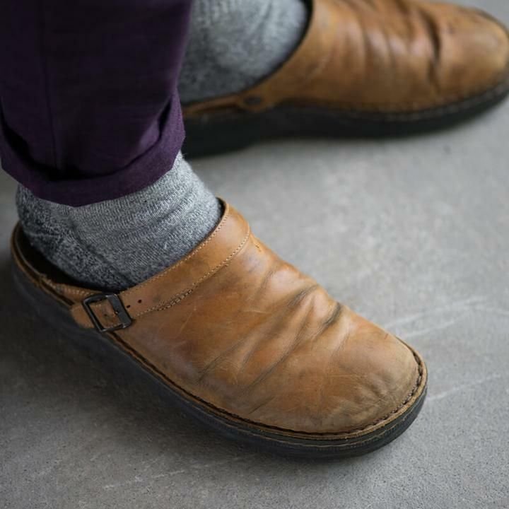 Chaussures en cuir marron usées avec chaussettes grises, style décontracté, sur sol en béton. Mode vintage, confort, tendance automne.