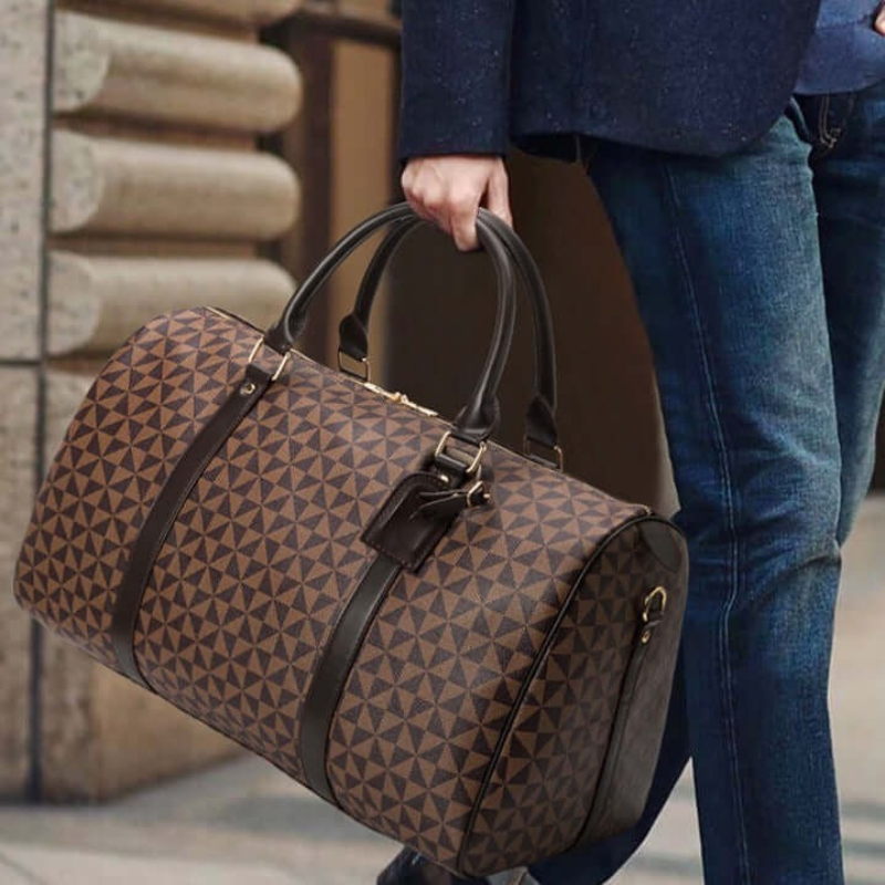 Mand bærer stilfuld brun weekendtaske med geometrisk mønster og læderhåndtag, perfekt til rejser og modebevidste mænd.