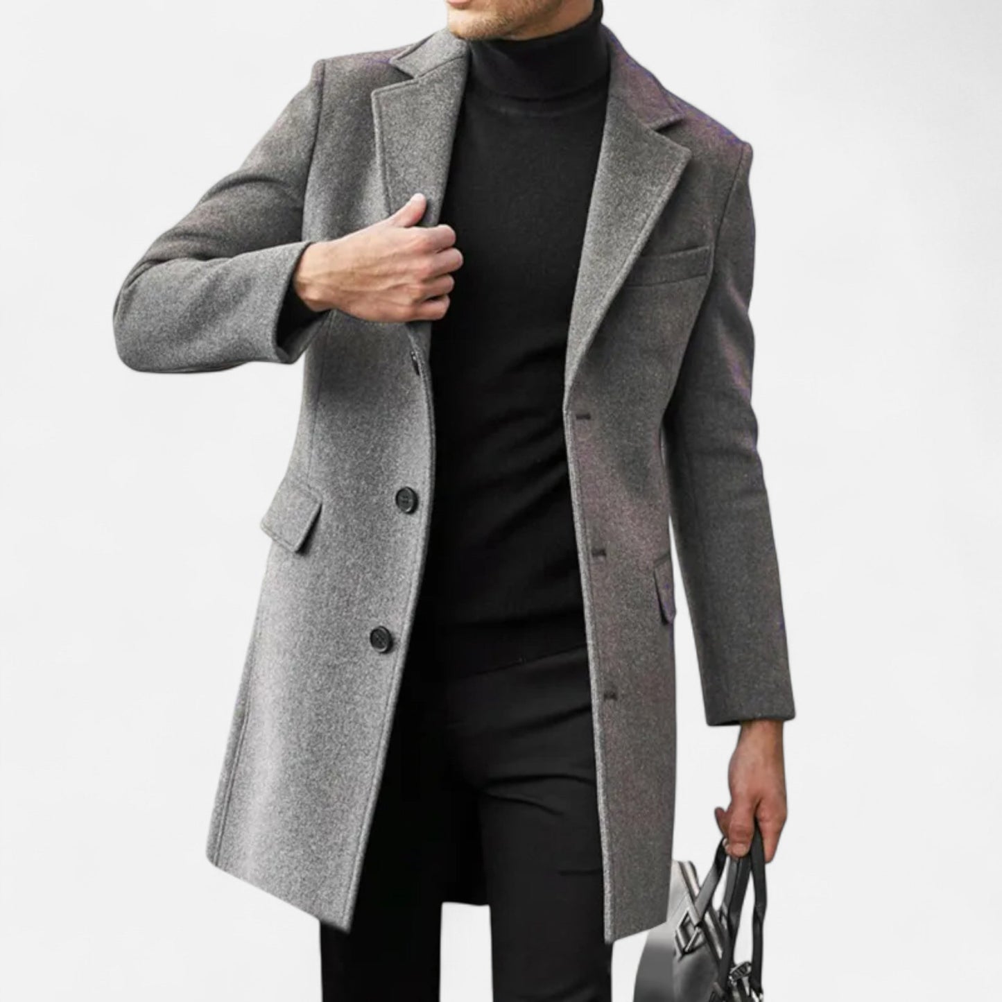Mand iført grå frakke og sort turtleneck, bærer en taske. Elegant herremode, vinterjakke, stilfuldt outfit til mænd.