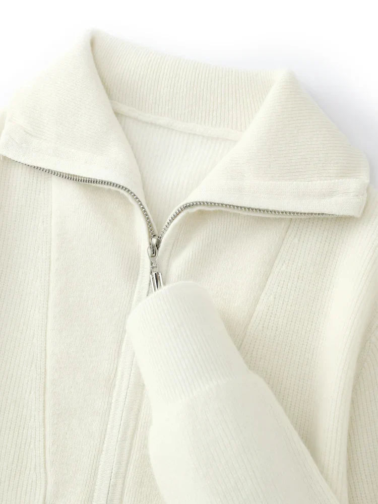 Gros plan sur un pull blanc en maille côtelée avec fermeture éclair argentée et col rabattu. Mode hiver, vêtement chaud et élégant.