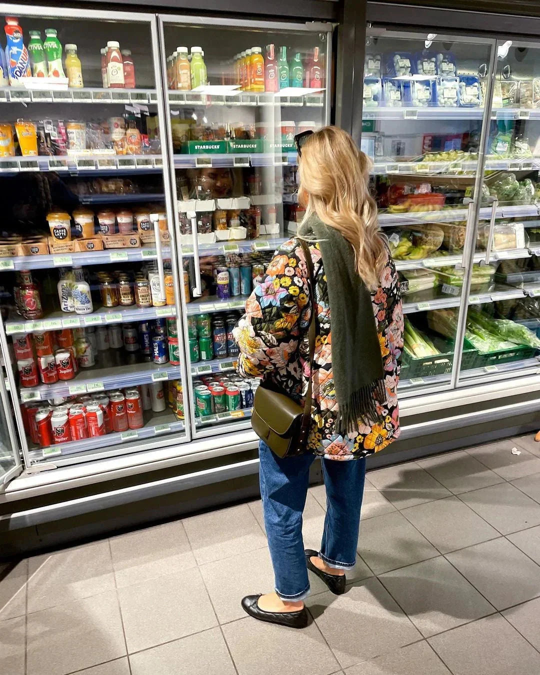 A multicolor floral puffer jacket for women displayed on a retail store shelf.
