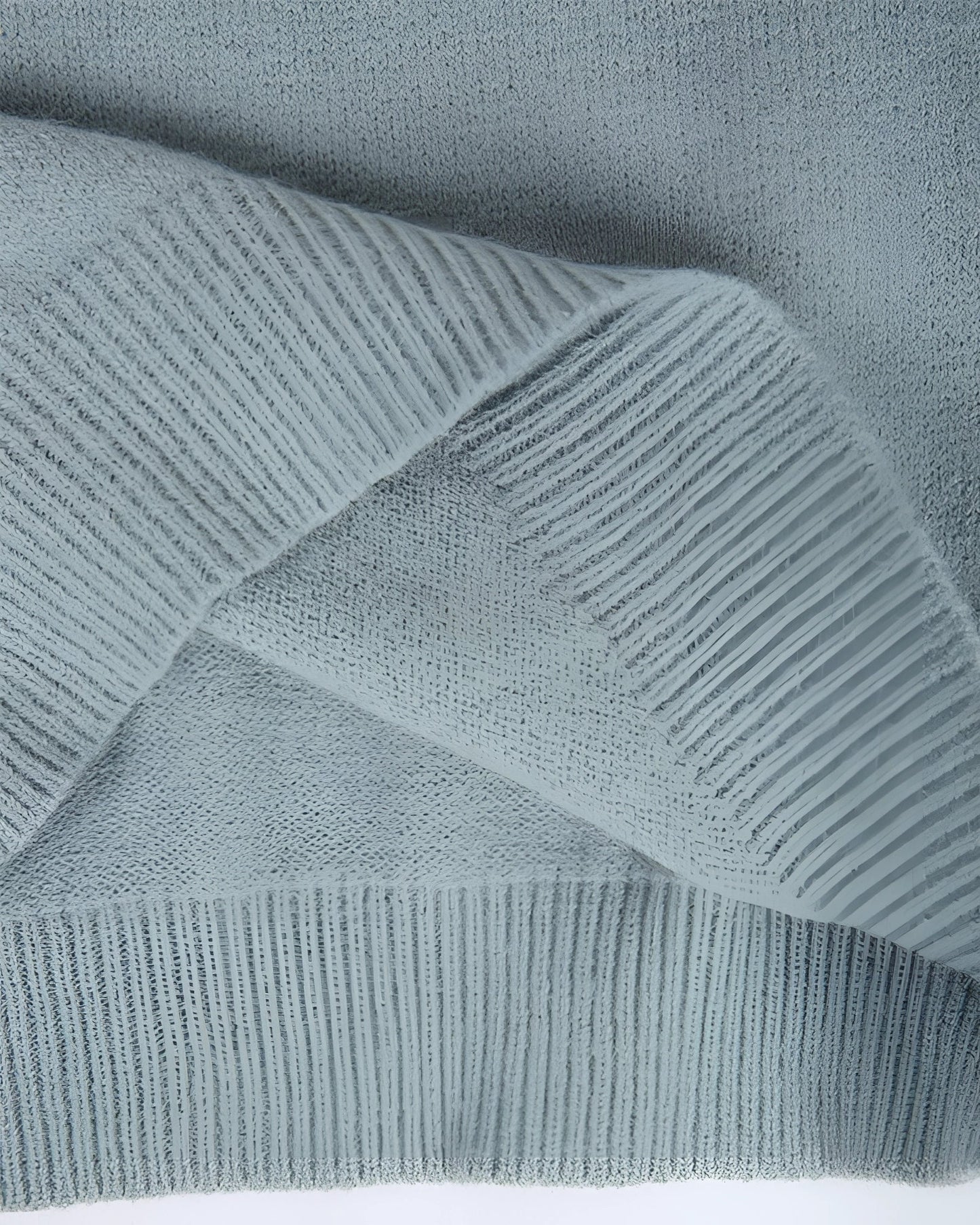 Mint green Fair Isle women's sweater with a cozy Scandinavian knit pattern, featuring intricate geometric designs in shades of grey and electric blue. The sweater is displayed against a wooden backdrop, highlighting the textile's texture and pattern.
