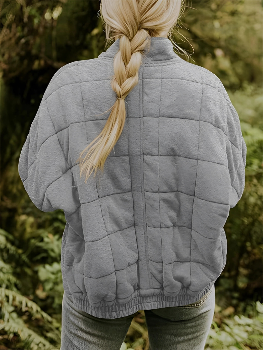 Women's lightweight insulated forest green quilted jacket displayed outdoors on grass, showing the jacket's design with long sleeves and quilted texture for warmth and style.