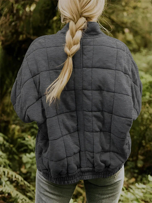 Women's lightweight insulated forest green quilted jacket with long sleeves, depicted outdoors in a natural setting.