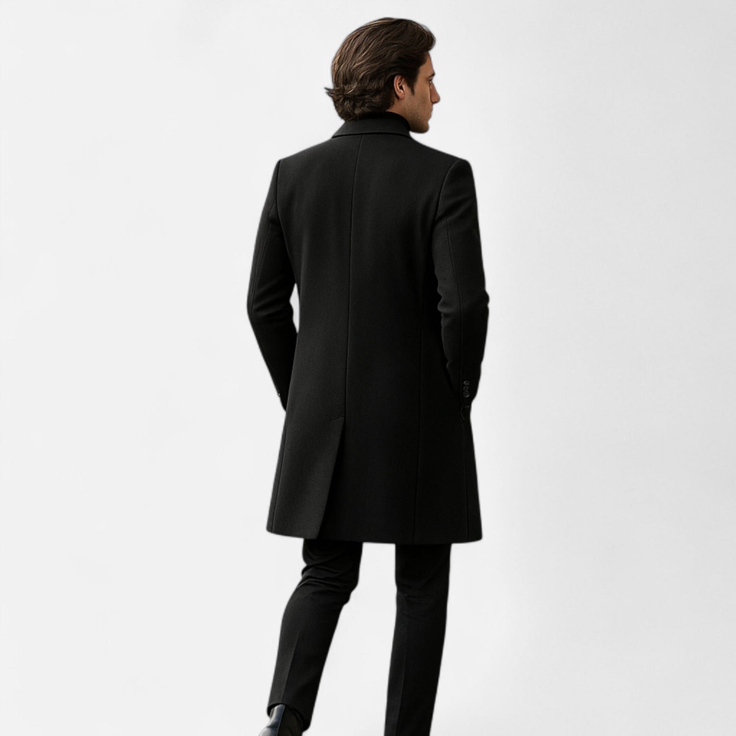 Mand i sort frakke set bagfra, elegant vintermode, stilfuldt herretøj, klassisk design, moderne look, minimalistisk baggrund.