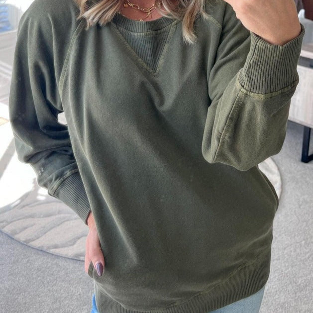 Femme portant un pull vert kaki, manches longues, col rond, style décontracté. Mode automne, tendance vêtements confortables.