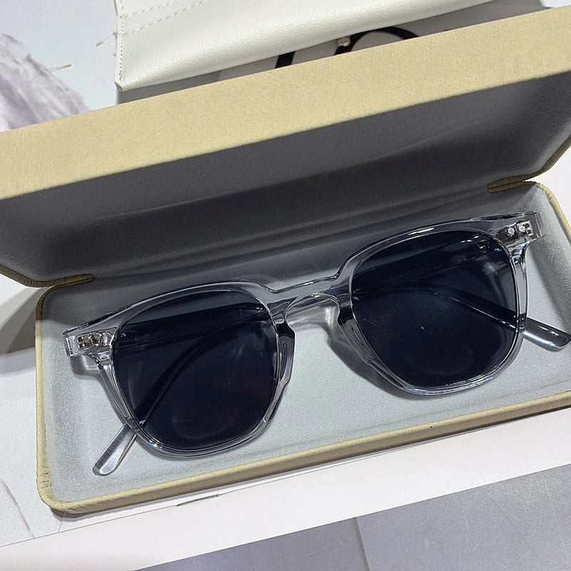 Lunettes de soleil transparentes dans un étui beige, verres teintés noirs, style moderne et élégant, accessoire de mode tendance.