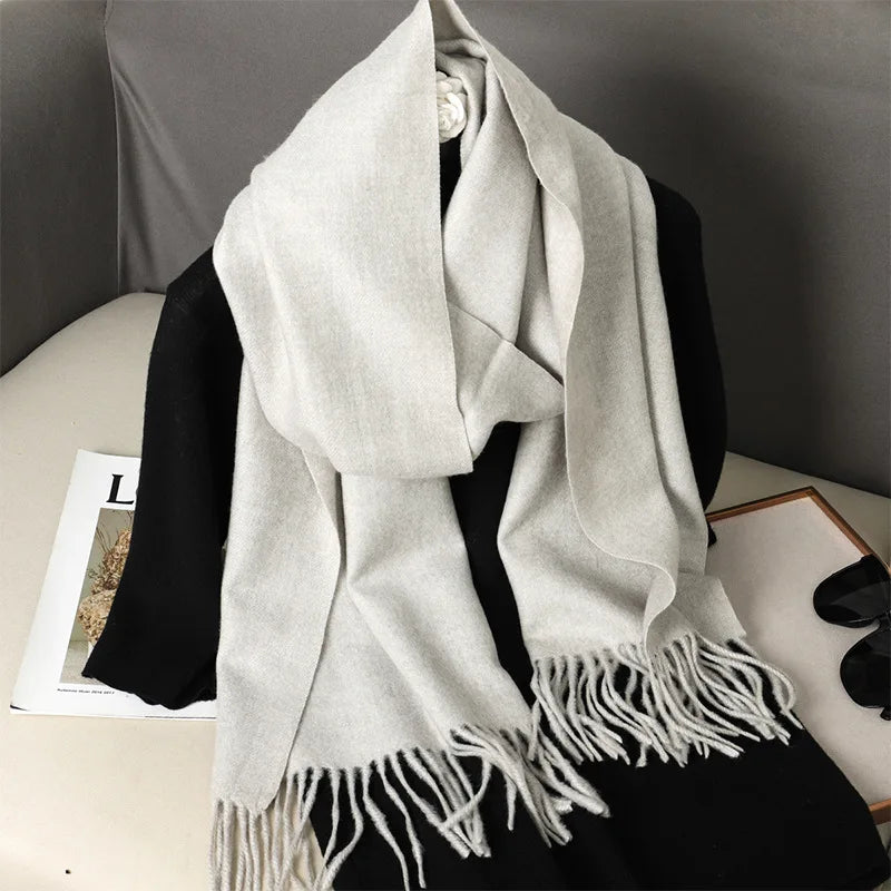 Lys beige kashmir tørklæde med frynser, elegant og blødt, placeret på sort baggrund. Perfekt til vintermode og stilfuldt tilbehør.