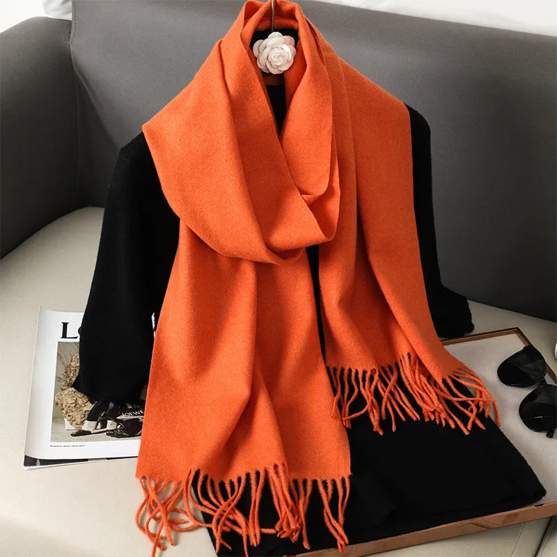 Orange uldhalstørklæde med frynser på sort jakke, elegant og varm til efterår og vinter. Perfekt tilbehør til modebevidste kvinder.