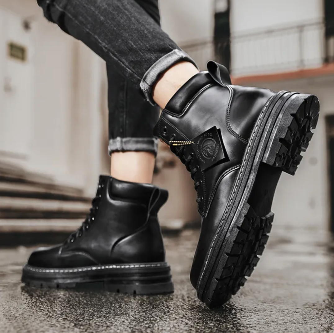 Bottes en cuir noir robustes pour homme, semelles épaisses antidérapantes, style urbain, mode automne-hiver, jeans retroussés.