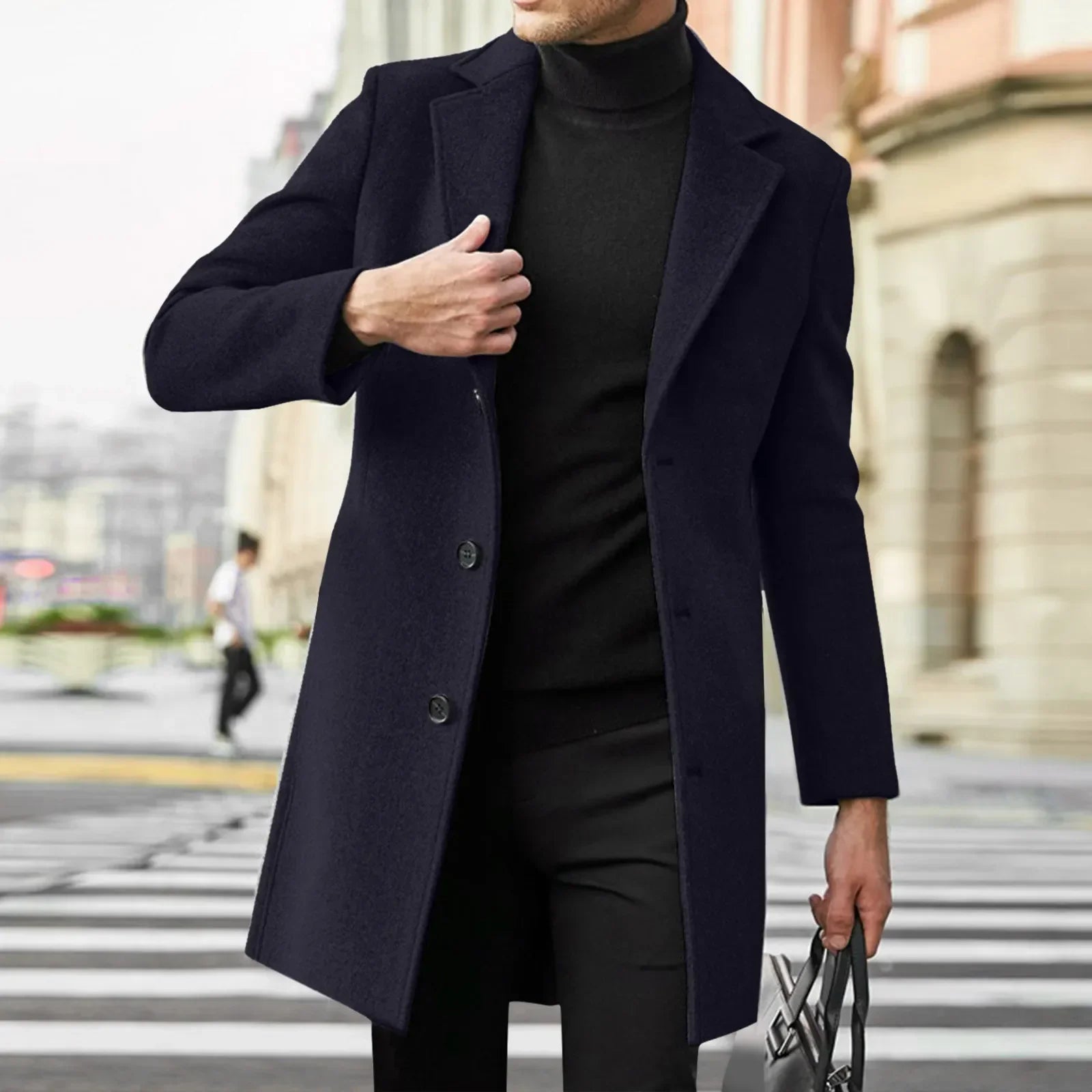 Mand iført sort frakke og turtleneck, krydser gade i bymiljø. Elegant herremode, vinterjakke, stilfuldt tøj til mænd, urban stil.