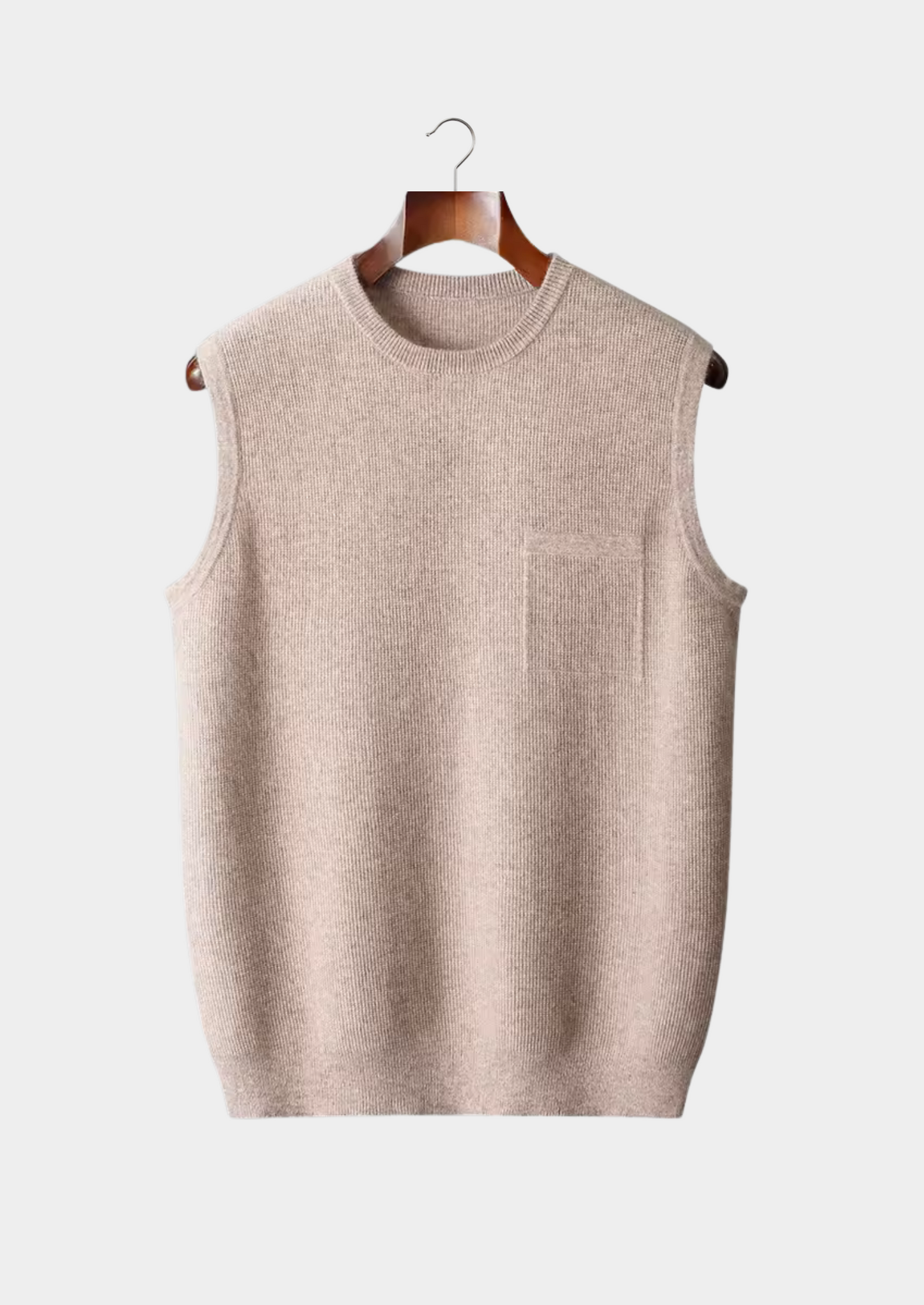 Gilet sans manches en tricot beige suspendu sur un cintre en bois, fond blanc. Mode automne-hiver, vêtement chaud et élégant pour homme.