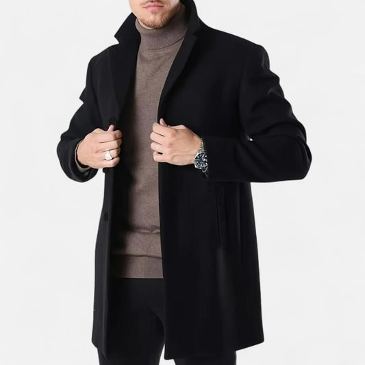 Mand iført sort frakke og brun rullekrave, viser stilfuldt herremode. Perfekt til efterår og vinter. Elegant look med ur og ring.